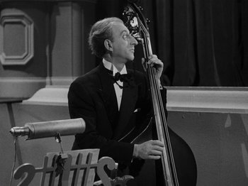Movie still from “Hellzapoppin'” (1941), directed by H.C. Potter – A black and white photo of a man holding a double bass; Medium shot, High angle