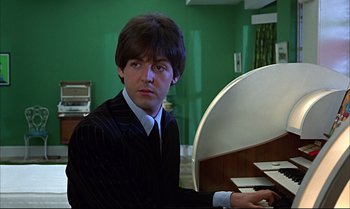 Movie still from “Help!” (1965), directed by Richard Lester – A man sitting in front of a piano in a room; Close Up shot, Low angle