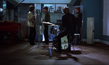 Movie still from “Help!” (1965), directed by Richard Lester – A group of people that are in a recording studio; Wide shot, High angle