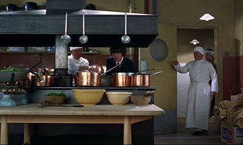 Movie still from “Help!” (1965), directed by Richard Lester – Two people in a kitchen preparing a meal; Wide shot, Low angle