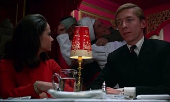 Movie still from “Help!” (1965), directed by Richard Lester – A man and a woman are sitting at a table; Medium shot, Low angle