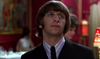 Movie still from “Help!” (1965), directed by Richard Lester – A person wearing a suit and tie; Close Up shot, Over the shoulder angle