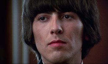 Movie still from “Help!” (1965), directed by Richard Lester – A person wearing a suit and a wig; Close Up shot, Low angle