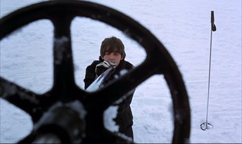 Movie still from “Help!” (1965), directed by Richard Lester – A man standing in the snow looking at a steering wheel; Medium shot, High angle