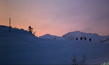 Movie still from “Help!” (1965), directed by Richard Lester – A group of skiers on a snowy hill at dusk; Extreme Wide shot, Low angle