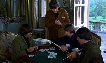 Movie still from “Help!” (1965), directed by Richard Lester – A group of people sitting at a table playing cards; Medium shot, High angle