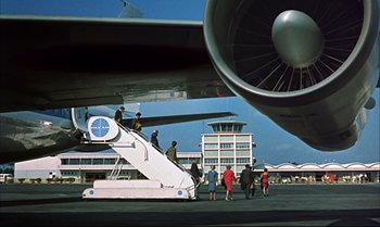 Movie still from “Help!” (1965), directed by Richard Lester – A group of people standing on the stairs of an airplane; Extreme Wide shot, Low angle