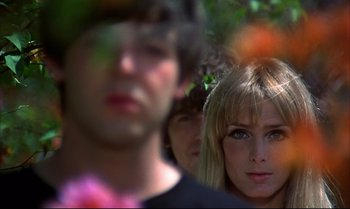 Movie still from “Help!” (1965), directed by Richard Lester – A woman and two men standing next to each other in a forest; Close Up shot, Over the shoulder angle