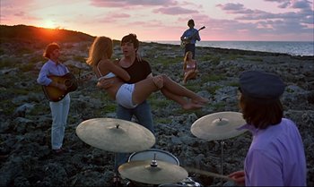Movie still from “Help!” (1965), directed by Richard Lester – A group of people standing on top of a rocky hill; Wide shot, High angle