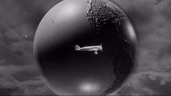 Movie still from “Henry & June” (1990), directed by Philip Kaufman – An airplane is flying through the air in a black and white photo; Extreme Wide shot, Overhead angle