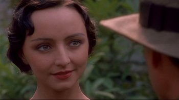 Movie still from “Henry & June” (1990), directed by Philip Kaufman – A woman's face in front of trees and bushes; Close Up shot, Over the shoulder angle