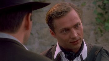 Movie still from “Henry & June” (1990), directed by Philip Kaufman – A person wearing a suit and hat; Close Up shot, Over the shoulder angle