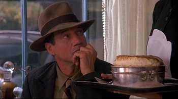 Movie still from “Henry & June” (1990), directed by Philip Kaufman – A man sitting at a table holding a tray of food; Close Up shot, Over the shoulder angle