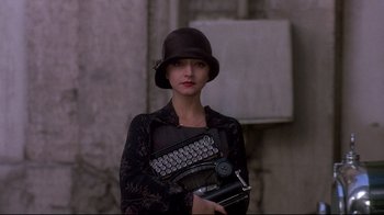 Movie still from “Henry & June” (1990), directed by Philip Kaufman – A woman in a black hat holding a typewriter; Close Up shot, Low angle