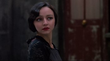 Movie still from “Henry & June” (1990), directed by Philip Kaufman – A woman in a black dress with red lipstick; Close Up shot, Over the shoulder angle