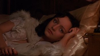 Movie still from “Henry & June” (1990), directed by Philip Kaufman – A woman laying in a bed wearing a white robe; Close Up shot, High angle