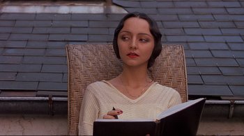 Movie still from “Henry & June” (1990), directed by Philip Kaufman – A woman sitting in a chair writing in a notebook; Close Up shot, High angle