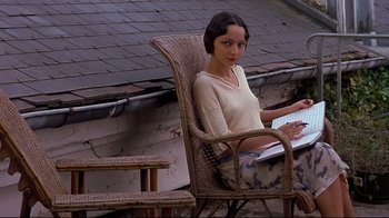 Movie still from “Henry & June” (1990), directed by Philip Kaufman – A woman sitting in a chair with a laptop; Medium shot, High angle