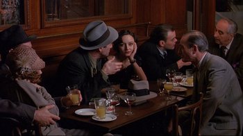 Movie still from “Henry & June” (1990), directed by Philip Kaufman – A group of people sitting at a table with drinks; Medium shot, Over the shoulder angle