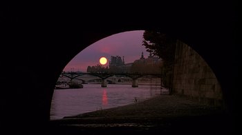 Movie still from “Henry & June” (1990), directed by Philip Kaufman – The sun is setting over a river and a bridge; Extreme Wide shot, High angle