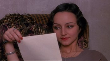 Movie still from “Henry & June” (1990), directed by Philip Kaufman – A woman sitting in a chair looking at a paper; Close Up shot, High angle