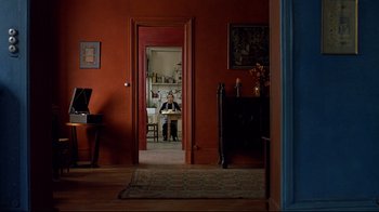 Movie still from “Henry & June” (1990), directed by Philip Kaufman – A person sitting in a room looking out a door; Wide shot, High angle