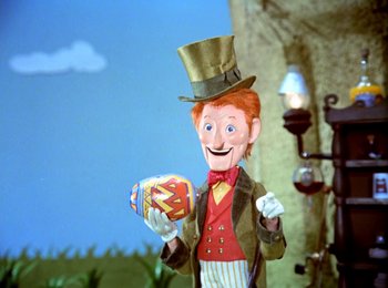 Movie still from “Here Comes Peter Cottontail” (1971), directed by Jules Bass – A man in a top hat holding a box of candy; Medium shot, Low angle