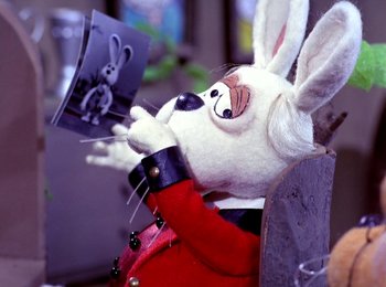 Movie still from “Here Comes Peter Cottontail” (1971), directed by Jules Bass – A stuffed rabbit sitting on top of a wooden chair; Extreme Close Up shot, Over the shoulder angle