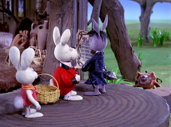 Movie still from “Here Comes Peter Cottontail” (1971), directed by Jules Bass – A group of stuffed animals sitting on top of a wooden table; Wide shot, High angle
