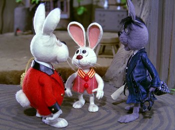 Movie still from “Here Comes Peter Cottontail” (1971), directed by Jules Bass – A group of stuffed animals that are standing in the dirt; Medium shot, High angle