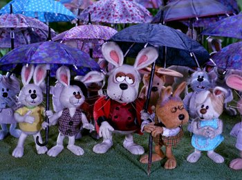 Movie still from “Here Comes Peter Cottontail” (1971), directed by Jules Bass – A group of stuffed animals holding umbrellas in the grass; Wide shot, High angle
