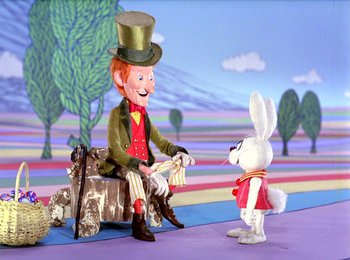 Movie still from “Here Comes Peter Cottontail” (1971), directed by Jules Bass – A white rabbit is standing next to a toy man; Wide shot, Over the shoulder angle