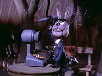 Movie still from “Here Comes Peter Cottontail” (1971), directed by Jules Bass – A toy rabbit is sitting in front of a phone; Medium shot, Low angle