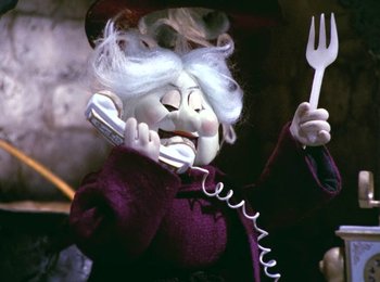 Movie still from “Here Comes Peter Cottontail” (1971), directed by Jules Bass – A doll is holding a phone and a fork in her hand; Close Up shot, High angle