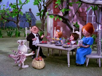 Movie still from “Here Comes Peter Cottontail” (1971), directed by Jules Bass – A group of people sitting at a table with food; Wide shot, High angle