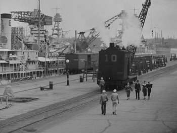 Movie still from “Here Comes the Navy” (1934), directed by Lloyd Bacon – A black - and - white photo of people walking on a street; Extreme Wide shot, High angle