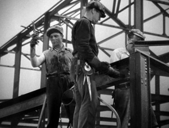 Movie still from “Here Comes the Navy” (1934), directed by Lloyd Bacon – A group of men standing on top of a metal structure; Medium shot, Low angle