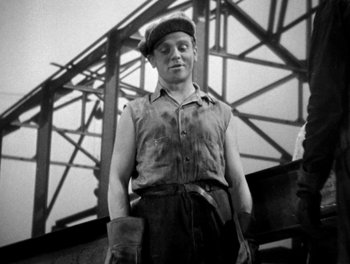 Movie still from “Here Comes the Navy” (1934), directed by Lloyd Bacon – A man standing in front of a metal structure; Medium shot, Low angle