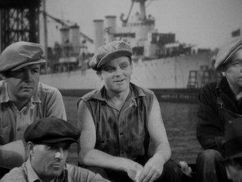 Movie still from “Here Comes the Navy” (1934), directed by Lloyd Bacon – An old black and white photo of a man sitting on a boat; Medium shot, High angle