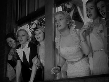 Movie still from “Here Comes the Navy” (1934), directed by Lloyd Bacon – A black and white photo of a group of women standing next to each other; Medium shot, Low angle