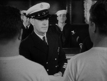 Movie still from “Here Comes the Navy” (1934), directed by Lloyd Bacon – A black and white photo of a man in a military uniform; Medium shot, Over the shoulder angle