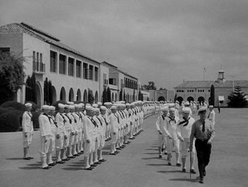 Movie still from “Here Comes the Navy” (1934), directed by Lloyd Bacon – A black and white photo of a line of men in uniform; Wide shot, High angle