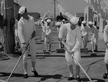 Movie still from “Here Comes the Navy” (1934), directed by Lloyd Bacon – A black and white photo of a group of men sweeping the street; Wide shot, High angle