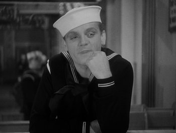 Movie still from “Here Comes the Navy” (1934), directed by Lloyd Bacon – A man in a sailor's uniform sitting at a table with his hand under his chin; Close Up shot, Over the shoulder angle