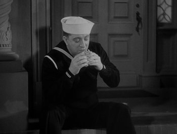 Movie still from “Here Comes the Navy” (1934), directed by Lloyd Bacon – A man in a sailor's uniform eating a sandwich; Medium shot, High angle