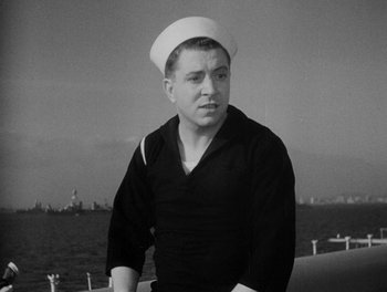 Movie still from “Here Comes the Navy” (1934), directed by Lloyd Bacon – A man in a sailor's uniform standing on a boat in front of the ocean; Medium shot, Low angle