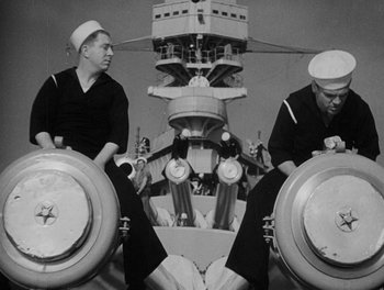 Movie still from “Here Comes the Navy” (1934), directed by Lloyd Bacon – Two sailors sit on the deck of an aircraft carrier; Medium shot, Low angle
