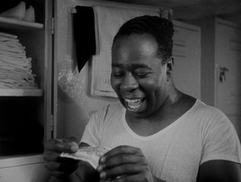 Movie still from “Here Comes the Navy” (1934), directed by Lloyd Bacon – A black and white photo of a man holding a piece of food; Close Up shot, Over the shoulder angle