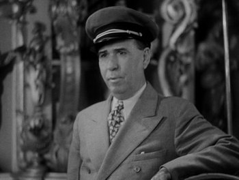 Movie still from “Here Comes the Navy” (1934), directed by Lloyd Bacon – An old photo of a man in a suit and a hat; Close Up shot, Low angle