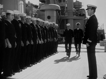 Movie still from “Here Comes the Navy” (1934), directed by Lloyd Bacon – A black and white photo of a line of men in navy uniforms; Wide shot, Low angle